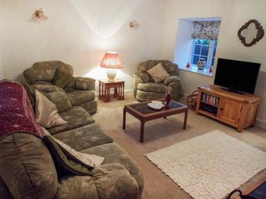 A living room with sofas, a coffee table and a television at Tyddyn Gyrfa Cottage Cemaes Bay