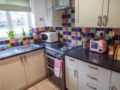 A kitchen with a sink and an oven at Tyddyn Gyrfa Cottage in Cemaes Bay