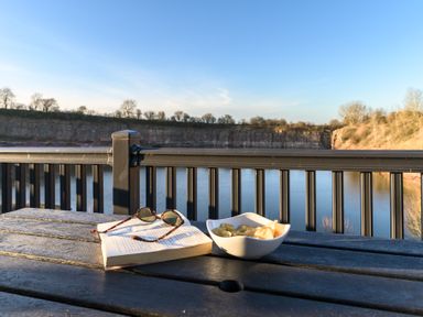 A table with a book and snacks near water at Pods by the Lake in Penrith