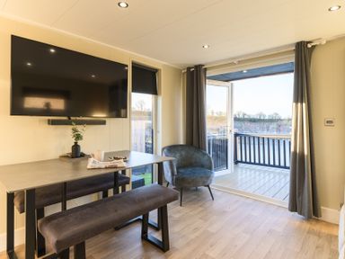 A living room with a television and dining table at Pods by the Lake in Penrith
