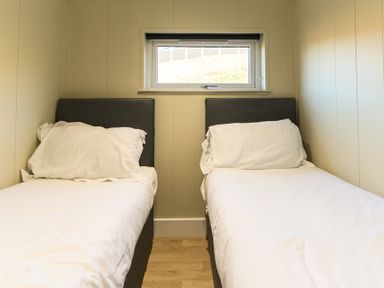 Two single beds with white bedding and a window at Pods by the Lake Penrith