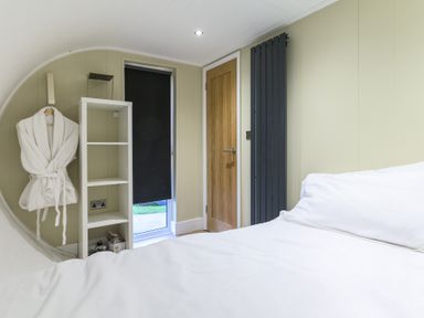 A bedroom with a bed and a shelf at Pods by the Lake Penrith