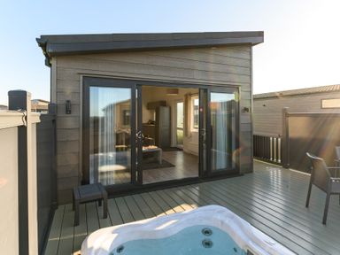 A hot tub on a deck with a cabin at Grasmere (Pet) Penrith