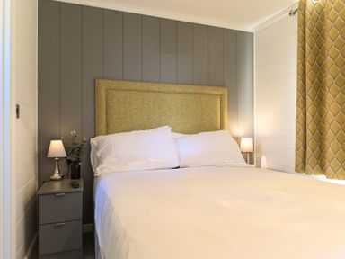A bedroom with a bed, headboard, bedside lamp, and curtains at Grasmere (Pet) Penrith