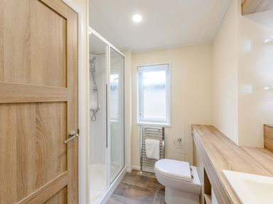 A bathroom with shower, sink, toilet, and towel rail at Keswick (Pet) Penrith