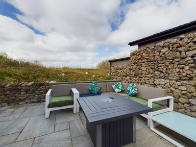 A garden area with an outdoor sofa and coffee table at Spa Sauna Lodge (Pet) Penrith