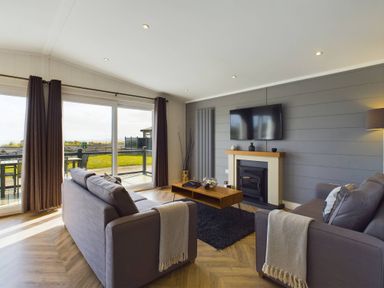 A living room with a sofa and television at Spa Sauna Lodge (Pet) in Penrith