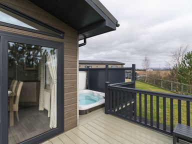 An outdoor deck with a hot tub and dining area at Helvellyn (Pet) Penrith