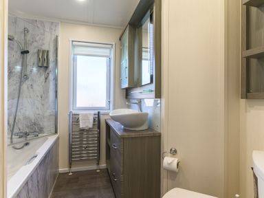 A bathroom with a bathtub, shower, sink and towel rail at Helvellyn (Pet) Penrith