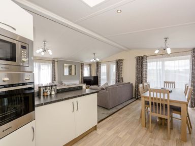A living room and dining area with a kitchen oven and dining table at Scaféll in Penrith