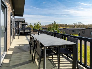 A deck with a table and chairs overlooking other houses at Scaféll (Pet), Penrith