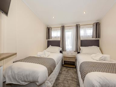 A bedroom with two beds, a nightstand, and a television at Scaféll (Pet) Penrith