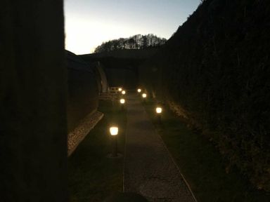 A pathway lit by lights with cabins and hedges at Pod 3 (No Pets) in Carnforth