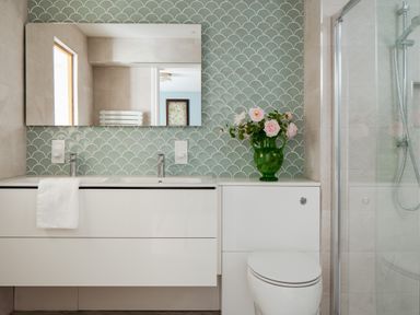 A bathroom with a sink, mirror, and flowers in a vase at The School House in Newton Abbot