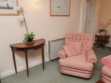 A living room with an armchair and side table at Grange Cottage in Belford