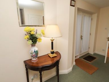A hallway with a table and lamp at Grange Cottage in Belford