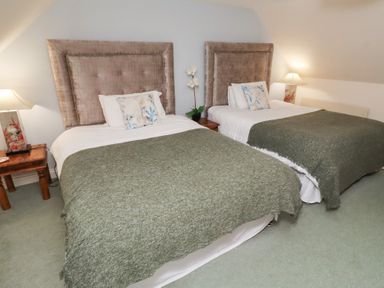 A bedroom with two beds and a lamp at Grange Cottage in Belford