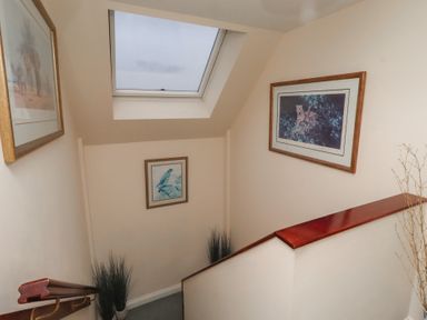 A staircase with wall art and a skylight at Grange Cottage in Belford