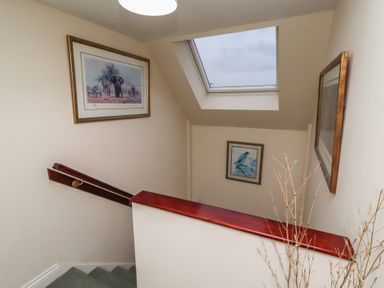 A staircase with paintings on the wall at Grange Cottage in Belford
