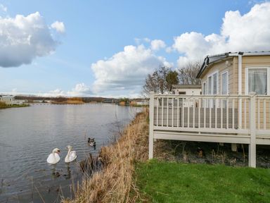 A deck by the water with swans and ducks at 62 Guddlebeck in Flookburgh