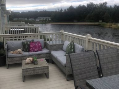 A patio with a sofa, coffee table, and a dog at 62 Guddlebeck, Lakeland Leisure Park, Flookburgh