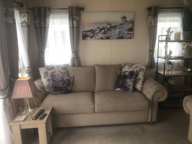 A living room with a sofa and lamp at 62 Guddlebeck in Lakeland Leisure Park, Flookburgh