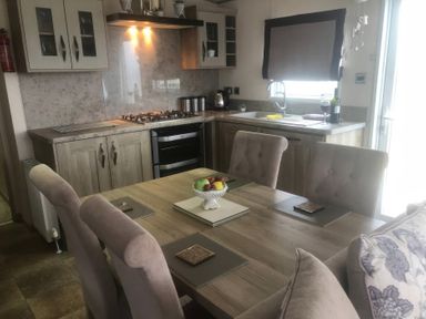 A dining room with a table and kitchen elements at 62 Guddlebeck in Lakeland Leisure Park, Flookburgh