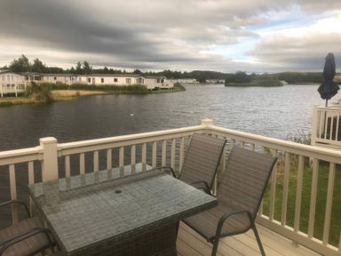 An outdoor area with a table and chairs overlooking the water at 62 Guddlebeck, Lakeland Leisure Park, Flookburgh