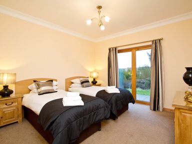A bedroom with twin beds and a door to the outside at The Braveheart (Pet) Dundee