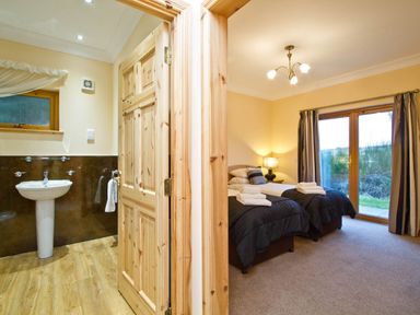 A bathroom with a sink and towel beside a bedroom with twin beds at The Braveheart (Pet) in Dundee