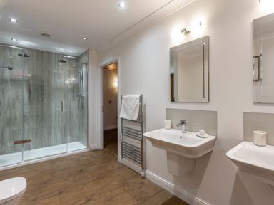 A bathroom with a shower, sink, mirrors, and towel rack at Byron Premier Spa in Dundee