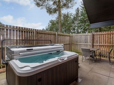 An outdoor area with a hot tub and seating at Byron Premier Spa (Pet) Dundee