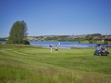 A golf course with golfers and a lake at Byron Premier Spa (Pet) Dundee