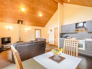 A living room with a sofa and kitchen counter at Muirloch Spa Plus (Pet) Dundee