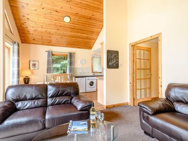 A living room with a sofa and glass table at Rainbow Lodge in Dundee