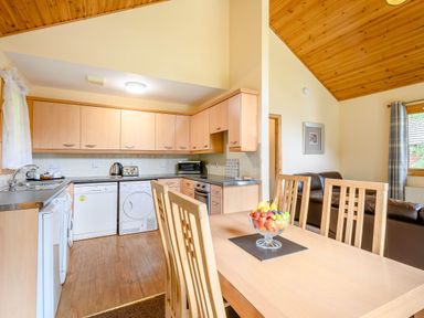 A kitchen with wooden cabinets and dining table at Barnard Lodge (Pet) Dundee