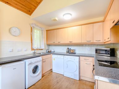 A kitchen with appliances including a washing machine, dishwasher, and microwave at Barnard Lodge (Pet) Dundee