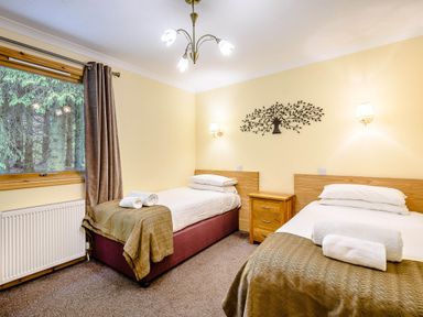 A bedroom with two beds and a window at Barnard Lodge (Pet) Dundee