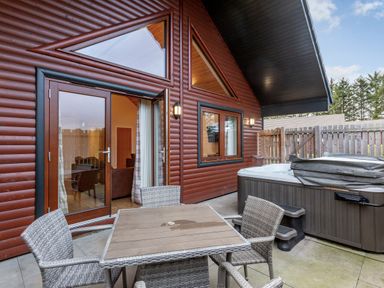 A patio with a table and chairs near a hot tub at Raeburn Premier Spa Dundee