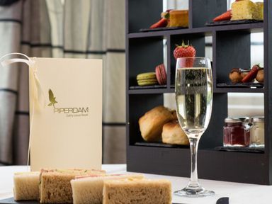 A table setting with champagne, sandwiches, and desserts at Piperdam Golf & Leisure Resort in Dundee