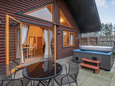 An outdoor area with a hot tub and table chairs at Rainbow Spa Plus (Pet) Dundee