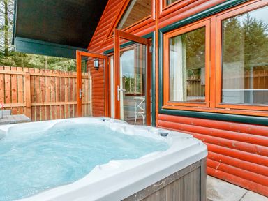 A hot tub with wooden deck and fence at Galbraith Premier Spa (Pet), Dundee