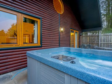 An outdoor area with a hot tub and windows at Osprey Spa Plus Dundee