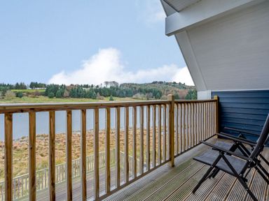 A balcony with chairs overlooking a lake at Lochside Premier Spa (Pet) in Dundee