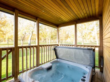 An outdoor area with a hot tub on a wooden deck at Belfry in Waltham