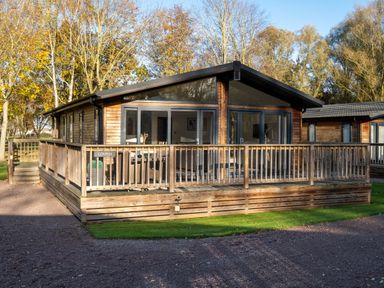 A wooden cabin with a deck and trees at Belfry in Waltham