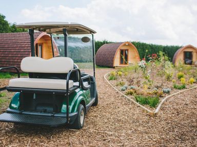 A golf cart in an outdoor area with wooden pods and flowers at Moonlight Spa Luxury in Waltham