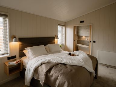 A bedroom with a bed and a bathroom door at Luxury One Bedroom Retreat in Waltham