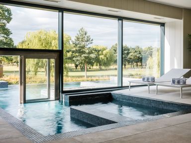 An indoor pool area with lounge chairs and large windows at Wentworth in Waltham