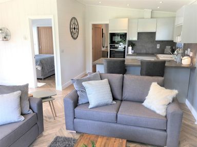 A living room with a sofa and kitchen area at Imperial View in Waltham